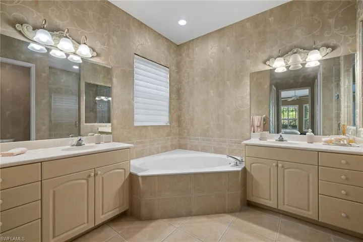 Full bath featuring a sink, two vanities, and wallpapered walls