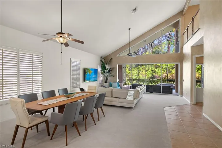 Dining room featuring high vaulted ceiling, ceiling fan, tile patterned flooring, visible vents, and baseboards