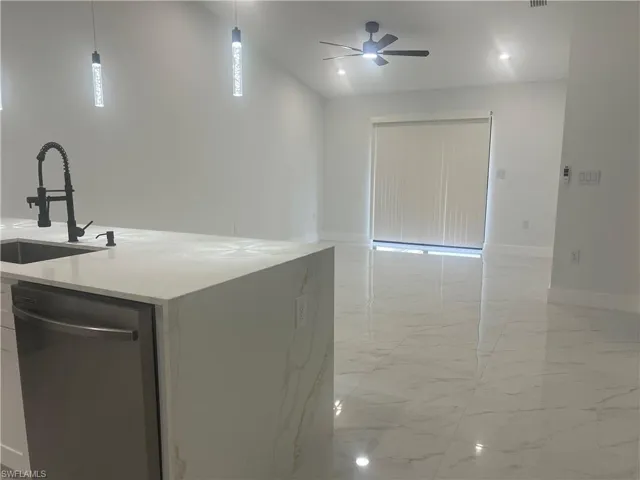 Kitchen with stainless steel dishwasher, open floor plan, light marble finish flooring, and a ceiling fan