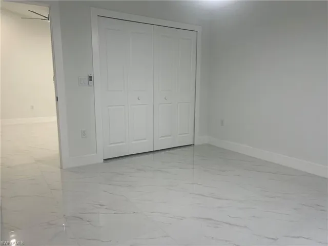 Unfurnished bedroom with light marble finish flooring and a closet
