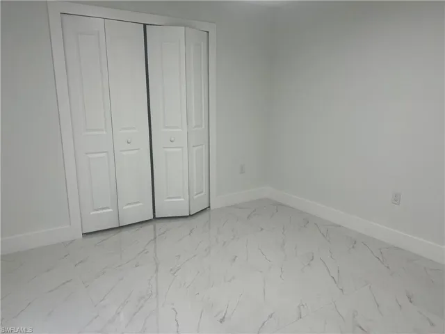 Unfurnished bedroom featuring light marble finish flooring and a closet