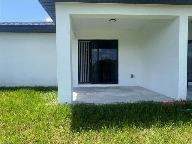 View of exterior entry with stucco siding and a patio area