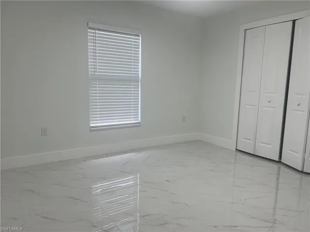Unfurnished bedroom featuring light marble finish floors and a closet
