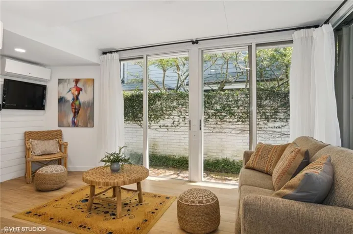 Living area with a wall unit AC and wood-type flooring