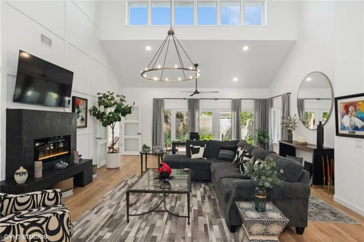 Great room featuring high vaulted ceiling, ceiling fan with chandelier, a electric fireplace, and LVT Tile  flooring.