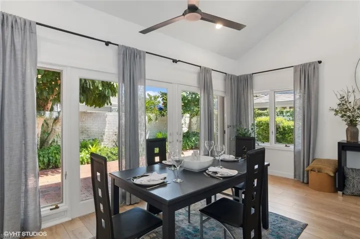 Dining room with vaulted ceiling, ceiling fan, french doors, and light hardwood / wood-style flooring