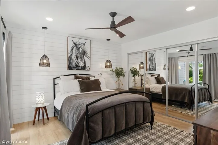 Bedroom with ceiling fan, a large mirrored closet, and ship lap accent wall.