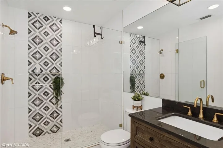 Guest Bathroom with tiled shower, oversized vanity, and toilet