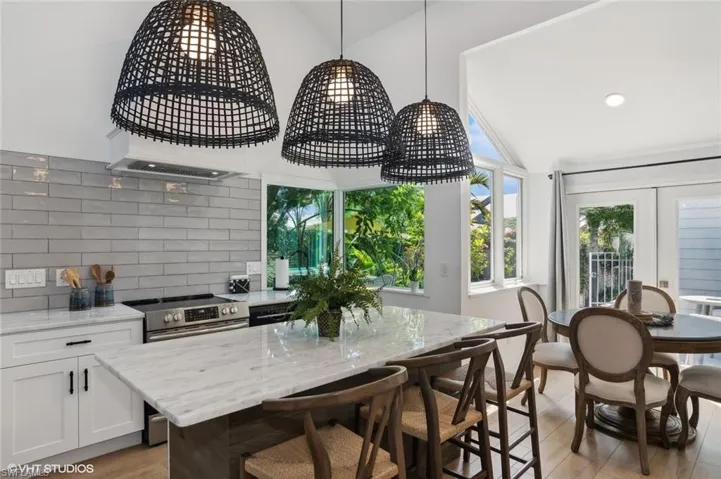 Kitchen with electric stove, tasteful backsplash, light wood-type flooring, and lofted ceiling