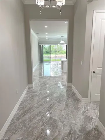 Corridor featuring crown molding, a chandelier, and marble tiled floors