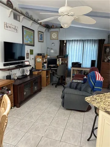 Living room featuring a ceiling fan, beam ceiling, and light tile patterned floors