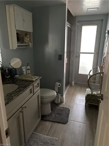 Full bathroom featuring wood finished floors, a stall shower, vanity, toilet, and visible vents