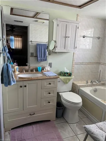 Full bathroom with bathtub / shower combination, vanity, ceiling fan, and toilet