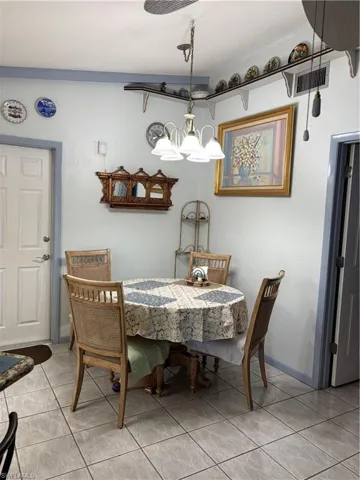 Dining room featuring light tile patterned flooring, visible vents, and an inviting chandelier
