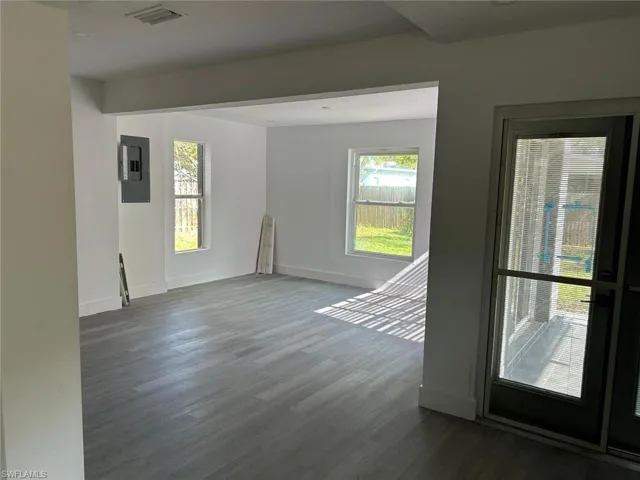 Unfurnished room featuring plenty of natural light, dark wood finished floors, and electric panel