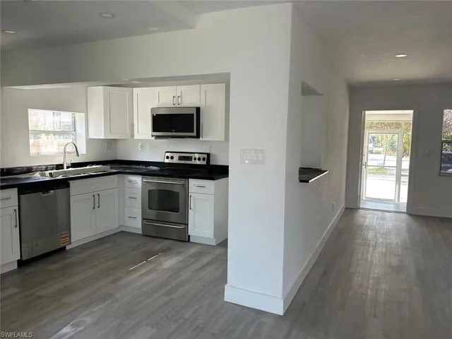 Kitchen with healthy amount of natural light, appliances with stainless steel finishes, white cabinetry, dark countertops, and recessed lighting