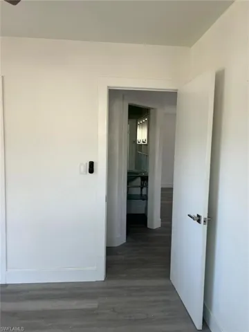 Corridor featuring dark wood-style flooring and baseboards