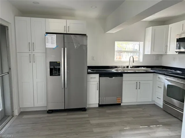 Kitchen with appliances with stainless steel finishes, white cabinets, and light wood-style floors