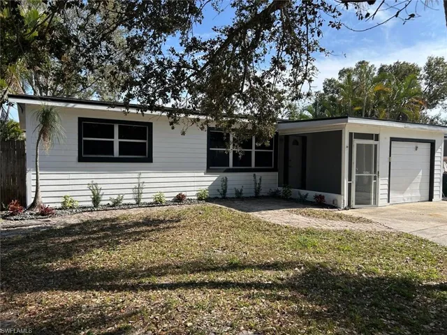 Ranch-style home with a sunroom, a front lawn, an attached garage, and driveway