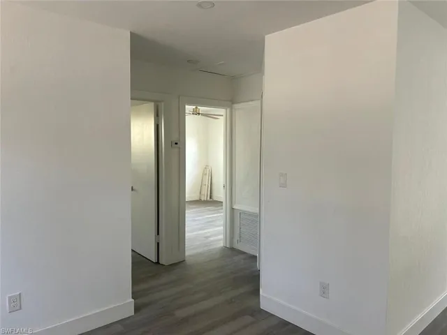 Hallway with dark wood-type flooring and baseboards