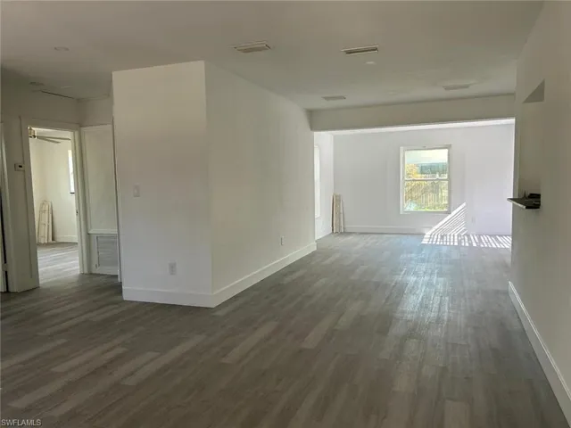 Spare room featuring dark wood finished floors and baseboards