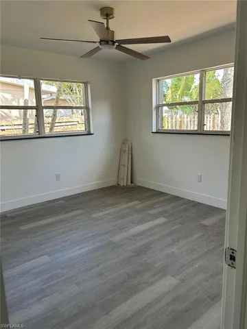 Unfurnished room featuring plenty of natural light, wood finished floors, and a ceiling fan