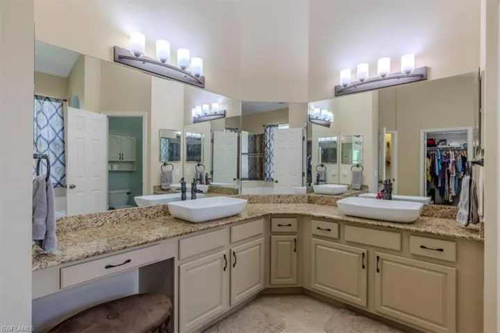Full bath featuring double vanity, a spacious closet, a shower with curtain, and light tile patterned flooring