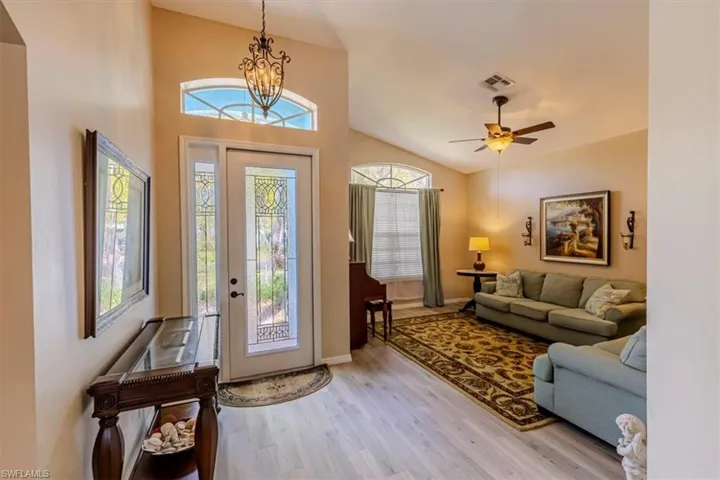 Foyer entrance with vaulted ceiling, a chandelier, wood finished floors, and ceiling fan