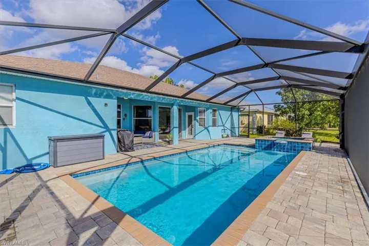 View of swimming pool featuring a patio area, a sunroom, a lanai, and a pool with connected hot tub