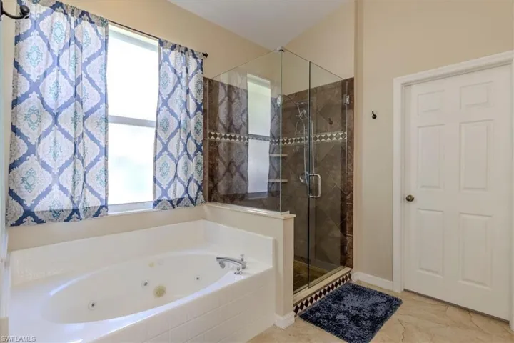 Bathroom featuring a jetted tub and a stall shower