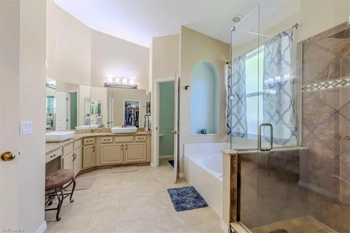 Full bath with a garden tub, a shower stall, vanity, and a spacious closet