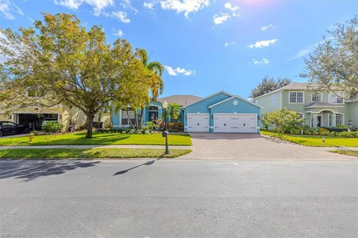 View of front of property with a front lawn, an attached garage, decorative driveway, a residential view, and stucco siding