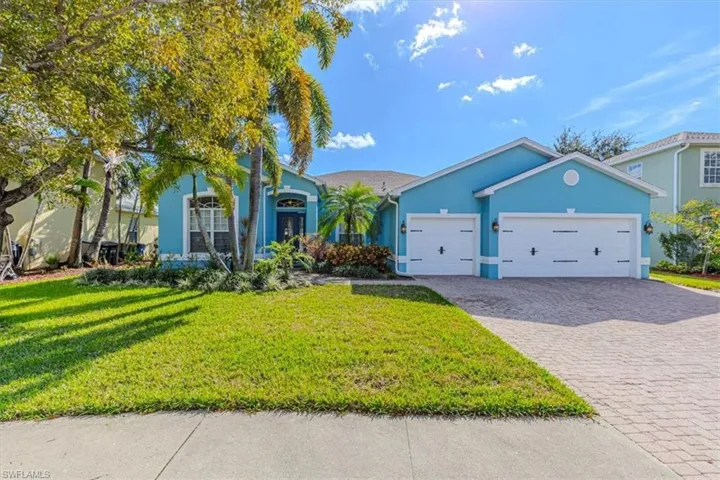 View of front of property with stucco siding, a front yard, decorative driveway, and a garage