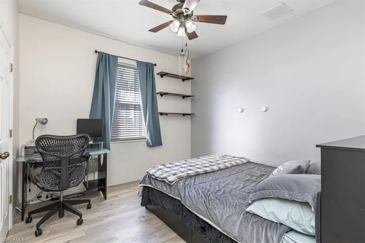 Bedroom with wood finished floors, a ceiling fan, and a desk