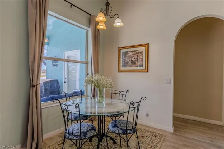 Dining space featuring arched walkways, a chandelier, and light wood-style flooring