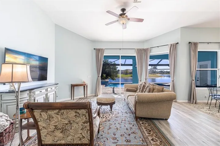Living room featuring a water view, ceiling fan, wood finished floors, and a sunroom