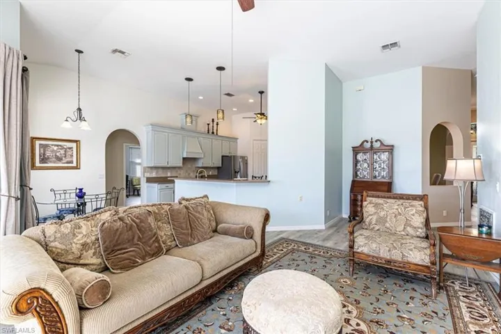 Living area featuring arched walkways, a ceiling fan, wood finished floors, and a chandelier
