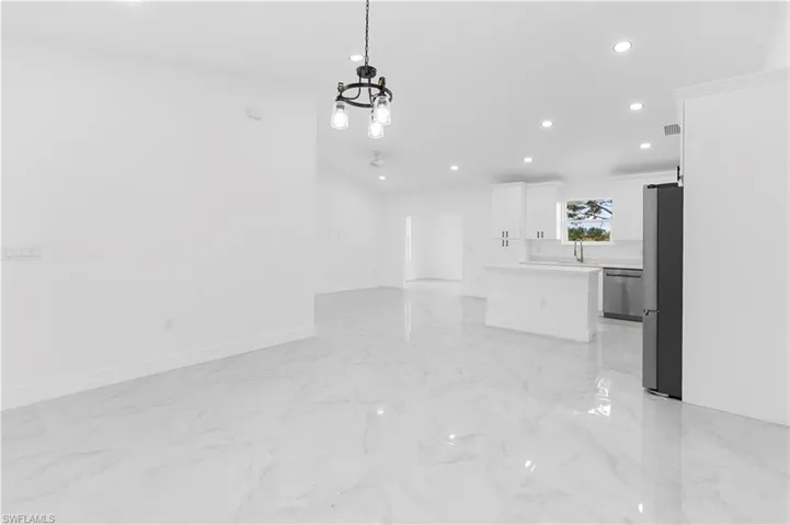 Unfurnished living room with recessed lighting, light marble finish flooring, a chandelier, and ceiling fan