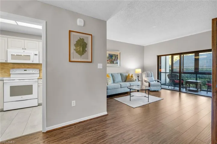 Living room with a textured ceiling and light hardwood / wood-style flooring