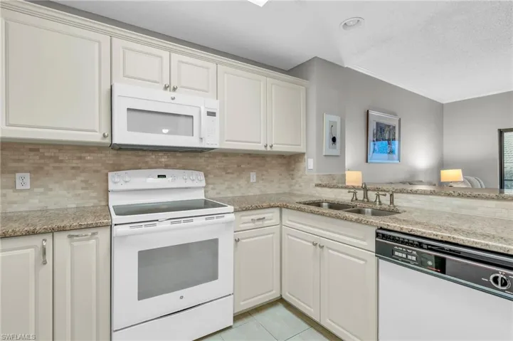 Kitchen featuring tasteful backsplash, sink, white cabinets, and white appliances