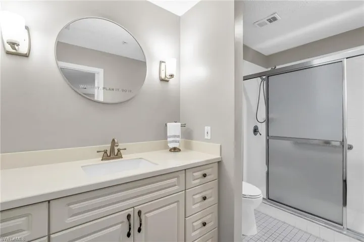 Bathroom with vanity, tile patterned floors, toilet, a textured ceiling, and a shower with shower door