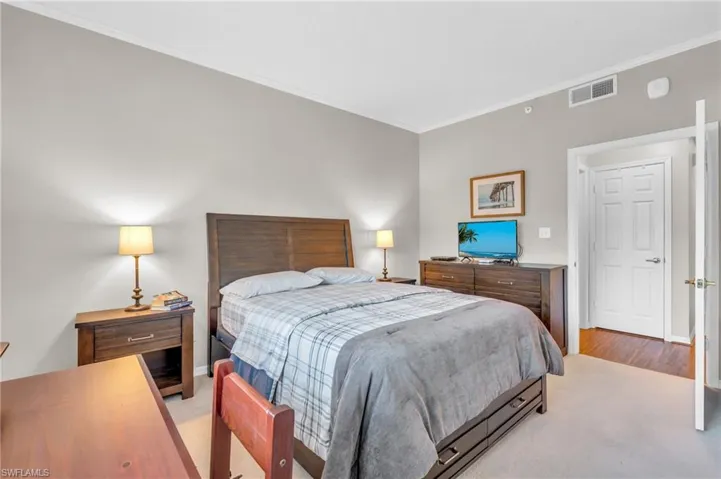 Bedroom featuring light colored carpet and crown molding