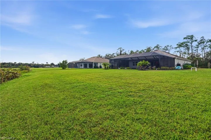View of grassy yard with a sunroom and glass enclosure