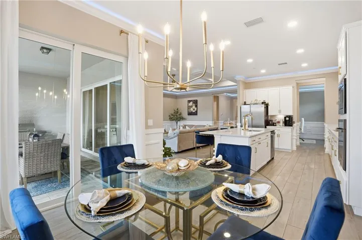 Dining space featuring a chandelier, ornamental molding, a decorative wall, a wainscoted wall, and light wood finished floors