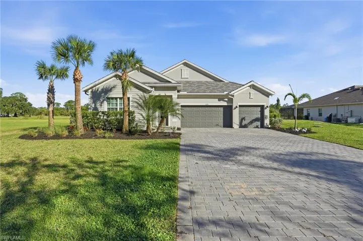 View of front of property featuring a front yard, decorative driveway, a garage, and stucco siding