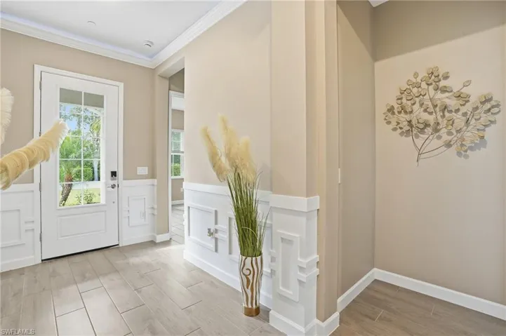 Foyer entrance with wood tiled floors, a decorative wall, wainscoting, and crown molding