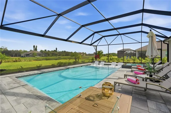 Swimming pool with a jacuzzi, glass enclosure, a sunroom, a patio, and a lawn