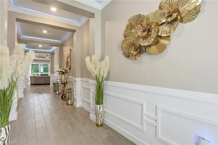Hallway with wainscoting, a decorative wall, wood finished floors, and crown molding