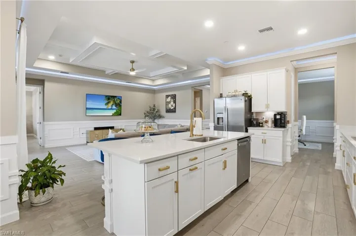 Kitchen with a decorative wall, a wainscoted wall, open floor plan, white cabinetry, and a ceiling fan
