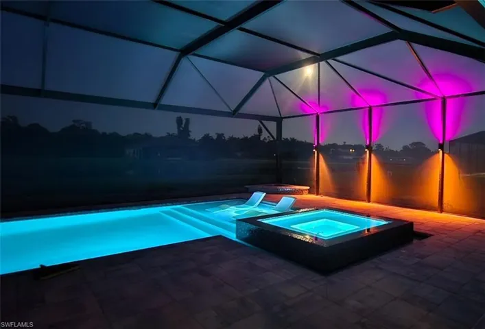 View of pool with glass enclosure and a pool with connected hot tub